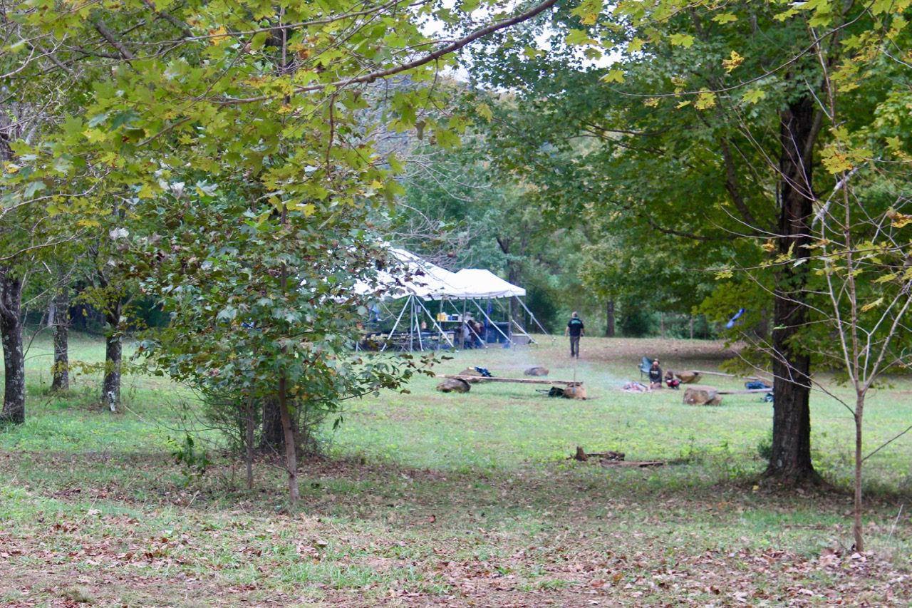 The main campsite at Spruce Creek, a large tent surrounded by benches, grills and trees.